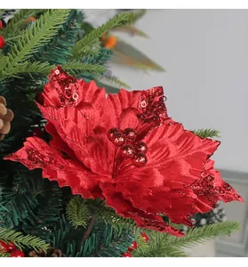 Primer plano detallado de una flor de Navidad roja con lentejuelas en una rama de pino.