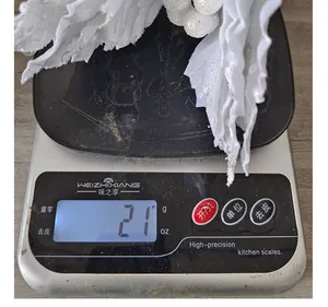 Vista detallada de una flor de Navidad artificial blanca que pesa 21 gramos en una báscula