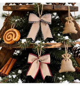 Fiocchi a quadri in finto lino e campane di iuta su un albero di Natale innevato.