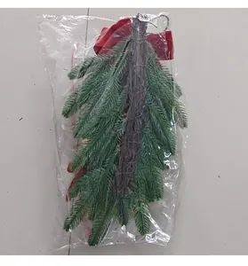 Detailed view of a green Christmas hanging swag with red velvet bow in a clear bag