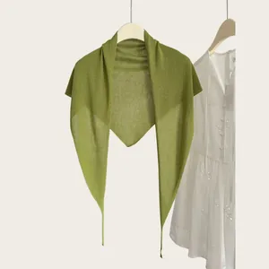 Detailansicht eines leichten grasgrünen gestrickten Dreieckstuchs am Kleiderbügel