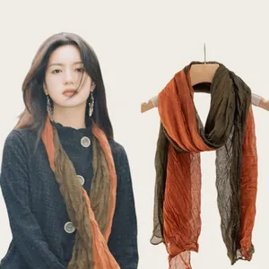 Close-up of lightweight pleated cotton linen scarf in orange and olive green shades