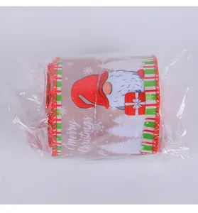 Macro view of Christmas burlap ribbon roll featuring a festive gnome and text pattern.