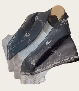 Detailed view of lightweight black square scarf with bow and chain print on hanger
