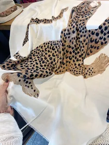 Vista detallada de una bufanda ligera con estampado de leopardo, textura suave y flecos