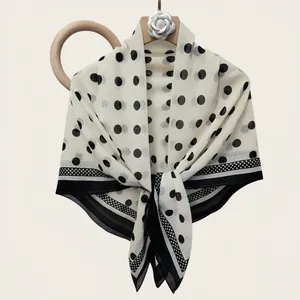 Elegant black and white polka dot silk cotton square scarf draped on a floral hanger