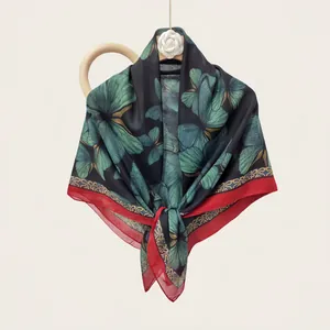 Detailed view of large square silk scarf featuring green butterfly wing patterns and red borders