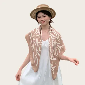 Elegante foulard in seta con motivo zebrato indossato come scialle estivo su abito bianco.