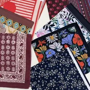 Detailed flat lay of various floral and geometric print silk scarves overlapping nicely.