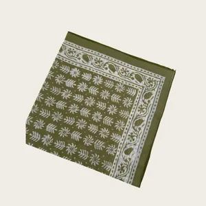 Detail of olive green scarf with white geometric and tribal pattern on fabric.