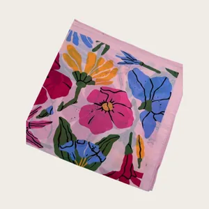 Macro detail showing vibrant floral patterns on a soft light pink summer silk scarf