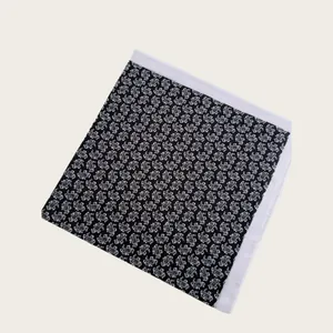 Detailed view of a black silk scarf with white paisley pattern and elegant white borders