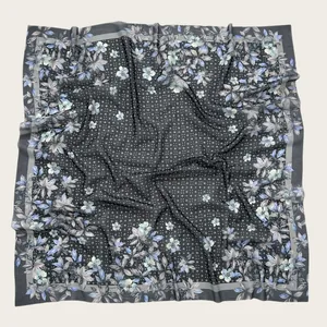 Detailed macro view of a floral print square scarf featuring decorative wave-cut edges