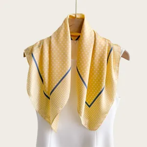 Elegante foulard in seta gialla a pois drappeggiato su un abito bianco per un look chic.