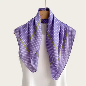 Vista dettagliata di un foulard di seta viola a pois drappeggiato su un manichino.
