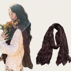 Detailed view of dark floral pleated cotton linen scarf shown with model wearing style