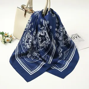 Detailed view of a navy blue satin square scarf with a white paisley pattern texture