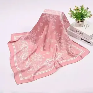 Detailed shot of a 90cm pink satin square scarf featuring white paisley flower patterns