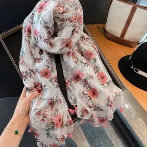 Close-up detail of lightweight floral scarf with elegant pink flower pattern and tassels
