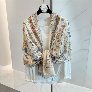 Detail view showing vintage floral vine print and blue tassel fringe on linen shawl