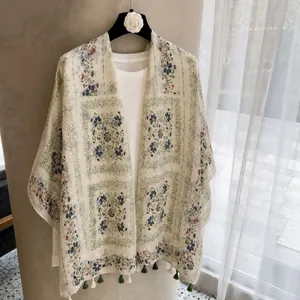 Detailed view of lightweight floral print sunscreen shawl with decorative green tassels