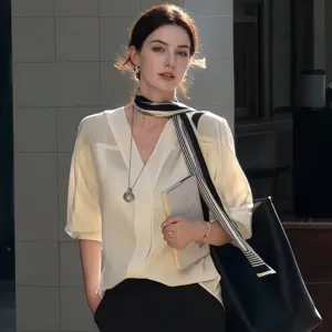 Foulard en soie rayé noir et blanc chic, porté avec un chemisier à col en V élégant.