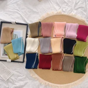 Collectie van geplisseerde effen zijden sjaals in verschillende kleuren.