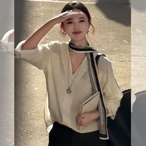 Détail élégant d'un foulard en soie rayé porté avec un chemisier blanc à col en V