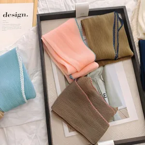 Gedetailleerd overzicht van geplooide sjaals in pasteltinten met elegante stiksels
