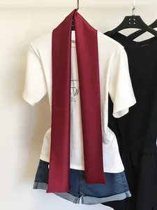 Détail d'une écharpe fine en soie rouge unie stylisée sur un t-shirt blanc classique