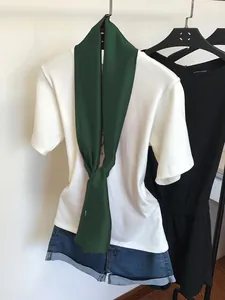 Vue détaillée d'une écharpe en soie étroite vert foncé nouée sur un t-shirt blanc