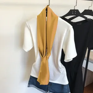 Gros plan d'une écharpe en soie fine jaune moutarde sur un t-shirt blanc