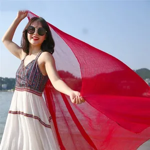 Vibrant red lightweight sun protection scarf for women elegantly styled on a sunny beach