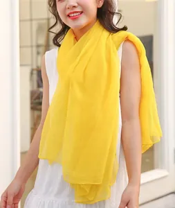 Close-up of lightweight yellow gauze scarf with subtle textured pattern on model.