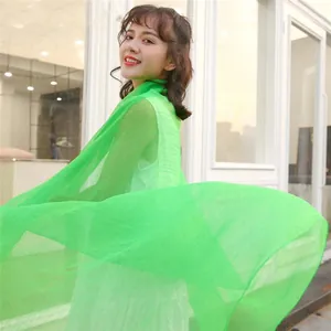 Elegant Asian model wearing a long flowing green sun-protection scarf in summer breeze