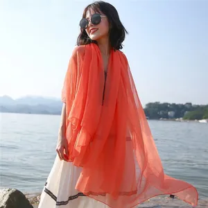 Elegant coral orange long sun protection shawl scarf for summer beach wear with soft texture.