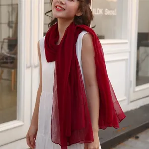 Detail of a lightweight deep red gauze scarf draped on a white dress