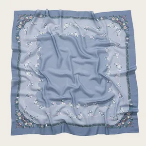 Detail view of a blue square scarf with delicate floral prints and wavy borders.