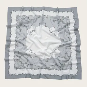 Detailed view of floral pattern and wavy cut edges on white and grey square hijab scarf.