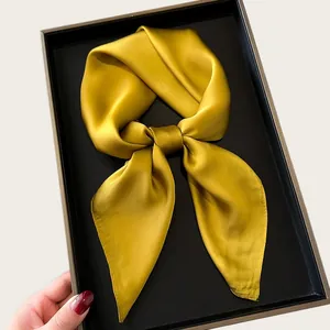 Mustard yellow silk-like satin square scarf tied in a bow presented in a black gift box