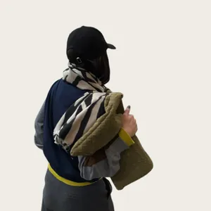 Vista detallada de una mujer con bufanda de cebra y bolso de tejido verde oliva