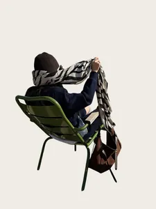 Vista trasera de una mujer con un chal con estampado de cebra en una silla verde