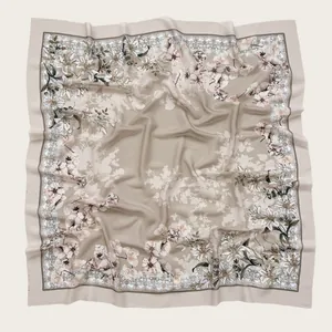 Detailed view of square floral print hijab with wave-cut edges in beige