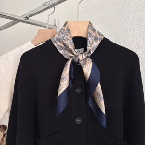 Dettaglio di un foulard in seta vintage con motivo paisley annodato su un cardigan nero