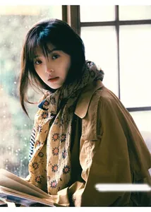 Atmospheric detail shot of a floral silk scarf styled with a khaki trench coat.