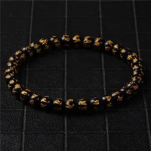 Detail shot of 6mm black stone beaded bracelet with gold Mantra symbols design