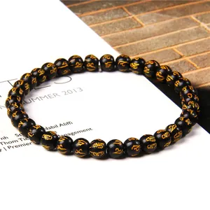 Detailed close-up of 6mm black beaded bracelet with gold mantra engravings.
