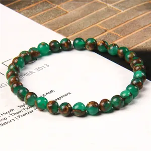 Macro detail of 6mm green and brown patterned stone beads on a stylish unisex bracelet