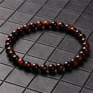 Macro view of 6mm reddish-brown tiger eye stone beaded bracelet on black grid background.