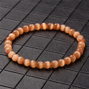 Close-up of 6mm orange cat's eye stone beaded bracelet on black grid background